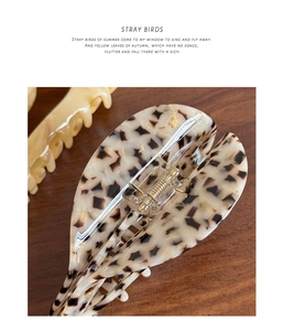 Detailed macro view of an oversized marbled acetate hair claw clip on a premium wood surface