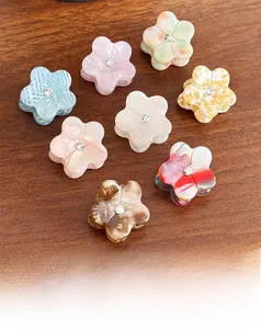Set of eight colorful acetate flower hair claws with crystal center on wood surface