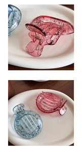 Detailed macro view of ink-patterned acrylic hair claws in pink and blue jelly colors
