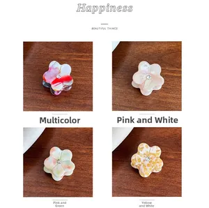 Detail of four mini flower hair clips with marble acetate texture and small rhinestones