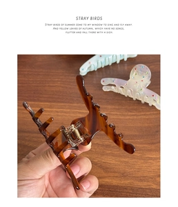 Detail view of brown tortoiseshell acetate hair claw clip with colorful rhinestones