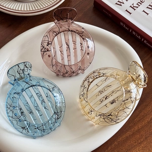 Ink line art hair claws in jelly blue, pink, and yellow colors on ceramic tray