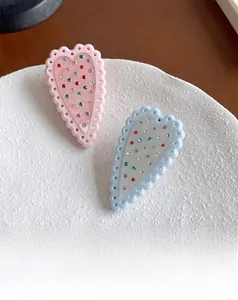 Dettaglio del fermaglio per capelli a cuore con bordi smerlati e strass colorati