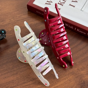 Elegant medium acetate shark hair claw clips set with colorful rhinestones on wood