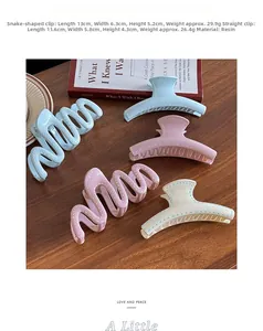 Détail de pinces à cheveux ondulées mates en crème, bleu et rose sur table en bois