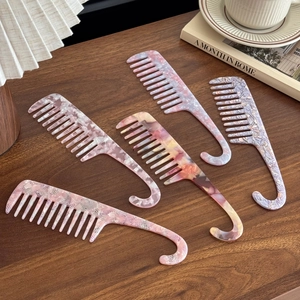 Lot de cinq peignes à dents larges en acétate avec manche à crochet sur une table boisée