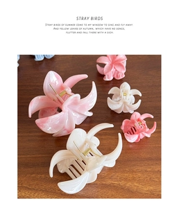 Detailed view of marble-textured floral hair clips with golden metal springs on wood