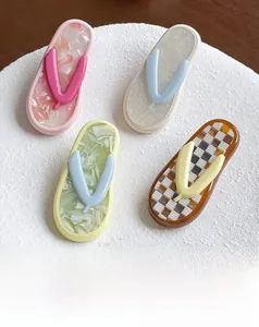 Close-up of four slippers-shaped acetate hair clips with marble and glitter textures