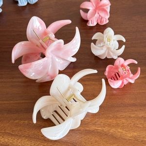 Floral hair claws in marble pink and cream white on a wooden surface in various sizes
