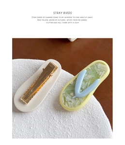 Set of two acetate hair clips in cream and marble green colors on a textured stand