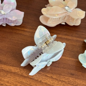 Iridescent bougainvillea flower hair claw clip with rhinestones on a wooden background