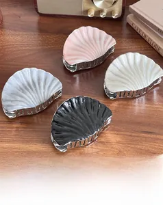 Detail showing shell-shaped hair claws in pink, white, gray, and black on a wooden desk