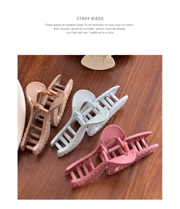 Three colorful matte hair claws with heart patterns on a natural wood background