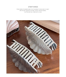 Detailed view of pearl white and pink shell-shaped hair claws on a warm wooden background