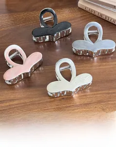 Detailed view of four colorful geometric heart hair claws on a warm wooden surface