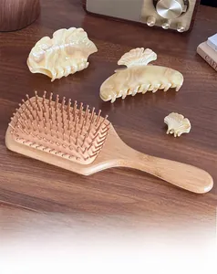 Close-up of marble texture acetate hair claws and wooden massage hairbrush on table
