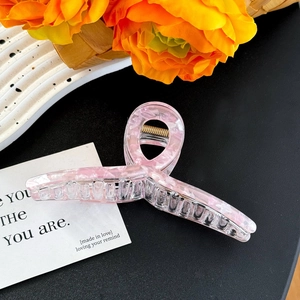 Detailed close-up of pink marble texture hair claw clip with golden metal spring