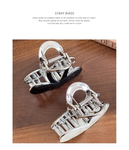Detailed view of glossy silver-plated hair claws in black glitter and cream on wood