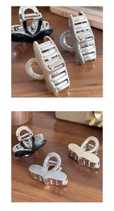 Detail of silver and black metal heart-shaped hair claws on a vintage wooden table