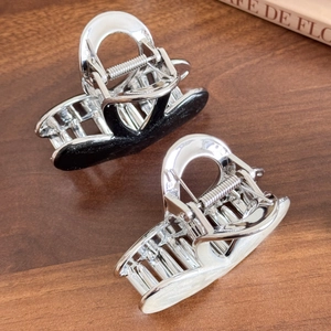 Elegant silver metal hair claw clips with resin heart inlay on a rustic wooden background