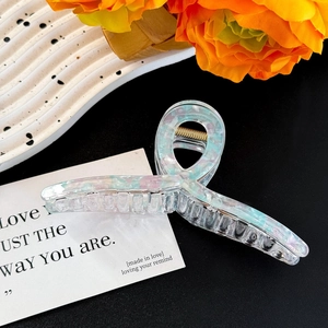 Detail view of large pearlescent claw clip with shell texture and metal spring mechanism