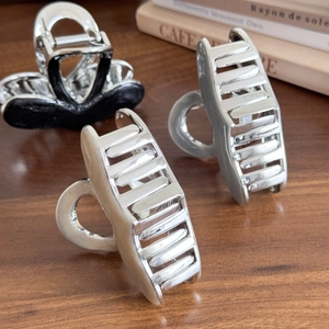 Elegant silver metal heart claw clip on vintage book aesthetic background for women