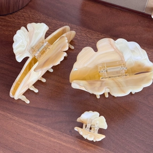 Three-piece marble texture hair claw clips set in cream and brown on a wooden surface