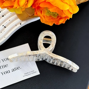 Close-up of a large marble texture hair claw clip with cream pearlescent finish and metal spring