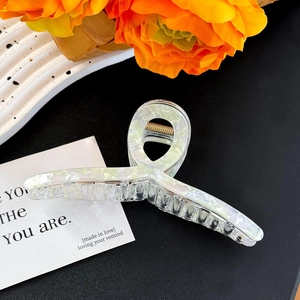 Detail of large marble white hair claw clip with golden spring on aesthetic tray