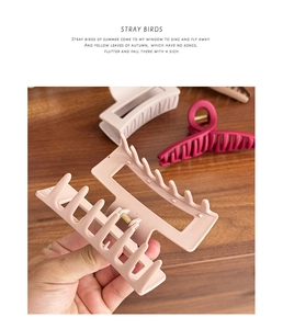 Close-up of matte silicone shark hair clips with strong metal spring on wood surface