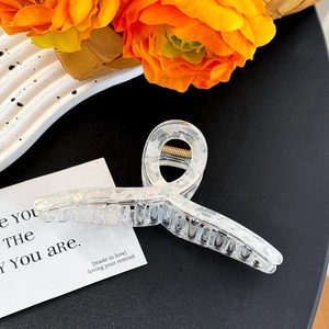 Detailed close-up of a large white marble acrylic hair claw clip on a stylish decorative tray