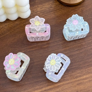 Lot de quatre pinces à cheveux carrées avec breloques fleurs souriantes sur table en bois