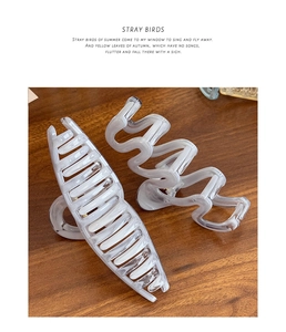 Detailed view of two marble pattern large hair claws with wave and crescent designs