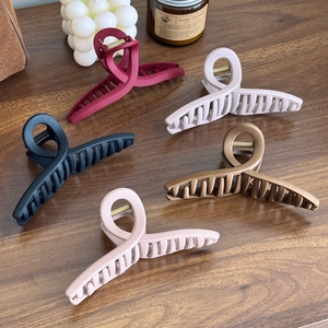 Five matte silicone shark hair claws in assorted colors on a textured wooden background
