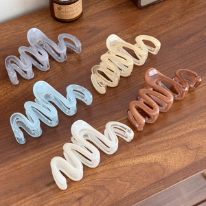 5-piece large wavy hair claws in translucent jelly Morandi colors on a dark wood table