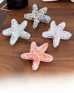 Detail of starfish acetate hair claws in four marble patterns on a wooden surface