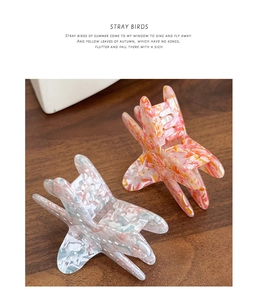 Detailed macro view of two marbled acetate starfish hair claws with gold glitter accents