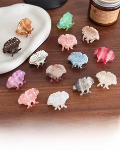 Flat lay of small ginkgo leaf acetate hair claws in various colors on a ceramic plate