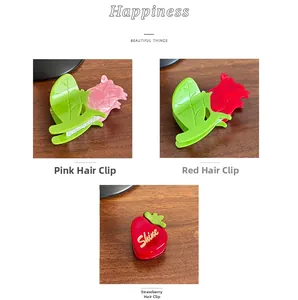Vue détaillée des pinces à cheveux en acétate fleur et fraise en rouge et rose