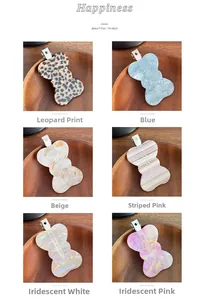 Set of six acetate bow hair clips in various patterns shown on wooden plate