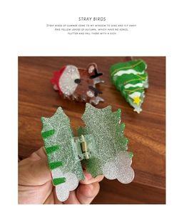 Detail of holly leaf resin hair claw with glitter finish and Christmas tree decorations