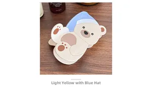 Dettaglio del fermaglio per capelli a orsetto crema con cappello blu su fondo legno