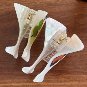Iridescent martini glass shaped hair claw clips with green olive motif on wood background
