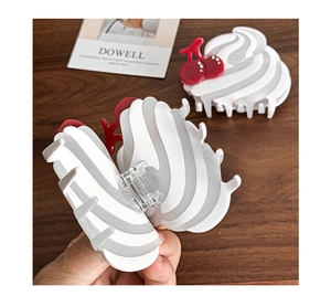 Détail de la pince à cheveux gâteau à la crème avec cerises rouges sur table en bois