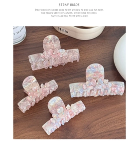 Detailed close-up of premium acetate flower hair claws with rhinestones on a wooden table