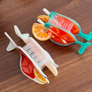 Cocktail shaped acrylic hair claw clips with orange slices on a wooden background