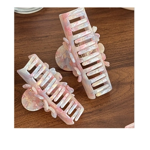 Detailed view of pink marble acetate flower hair claw clips on wood background