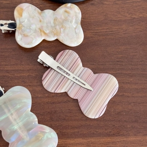 Elegant bow-shaped acetate hair clips in marble and gradient patterns with metal grips