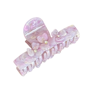 Pink marble acetate hair claw with floral accents and sparkling crystals on white background
