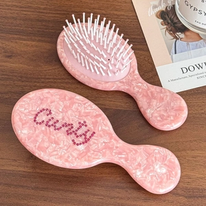 Pink marble pattern air cushion hairbrush with Queen rhinestone detail on wooden table